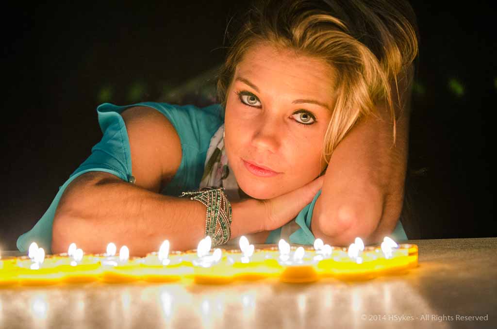 Portrait of a model with birthday cake and lit by candlelight